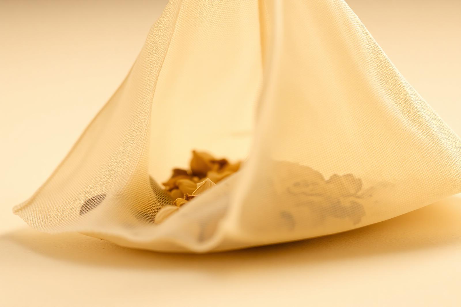 Macro of a plant-fiber tea filter bag with dried botanicals
